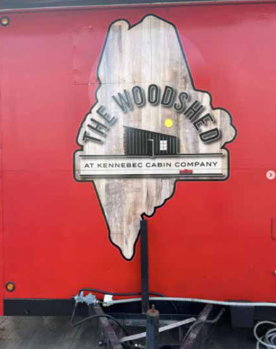 A red wooden panel with The Woodshed logo